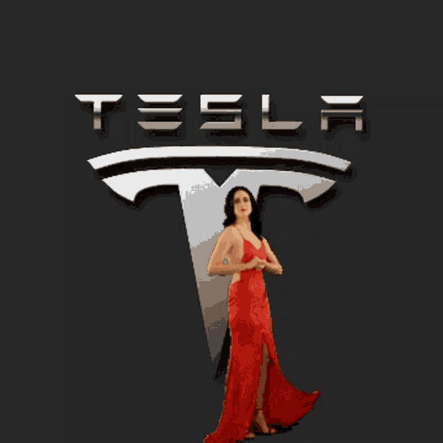 a woman in a red dress is posing in front of a tesla logo