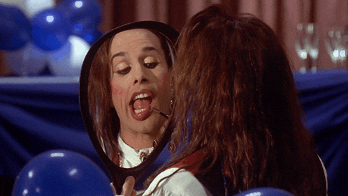a woman is looking at herself in a mirror with her tongue out