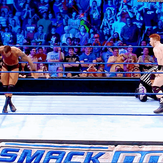 two wrestlers in a wrestling ring with a sign that says smack do