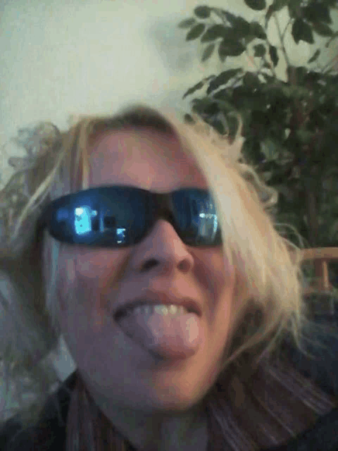 a woman wearing sunglasses sticking her tongue out