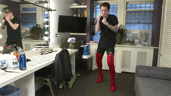 a man in a black shirt and red boots is standing in front of a mirror