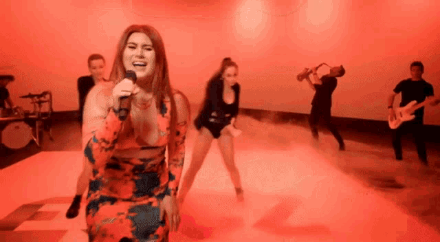 a woman singing into a microphone in front of a group of people