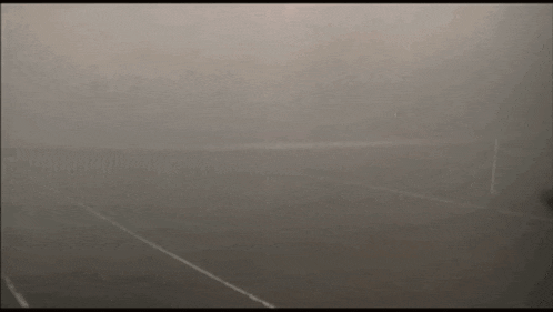 a man is playing tennis in a foggy court