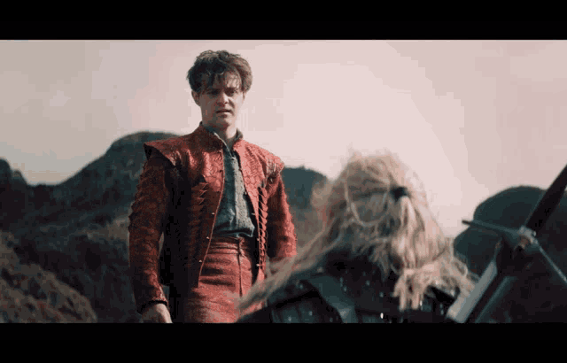 a man in a red jacket is standing next to a woman