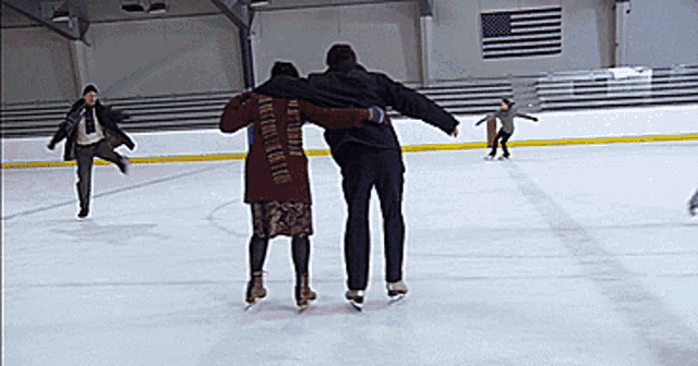 a man and a woman are ice skating on a rink in front of an american flag