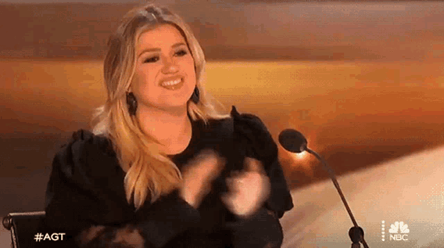a woman is sitting in front of a microphone and clapping .