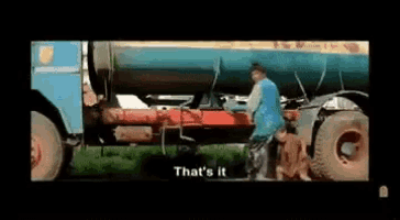 a man is standing next to a tanker truck with the words `` that 's it '' written on it .
