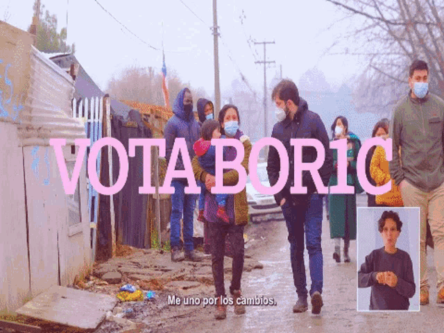 a group of people wearing face masks are walking down a street with the word vota boric in pink letters