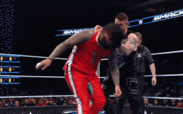 a wrestler is standing in a wrestling ring with a referee standing behind him .