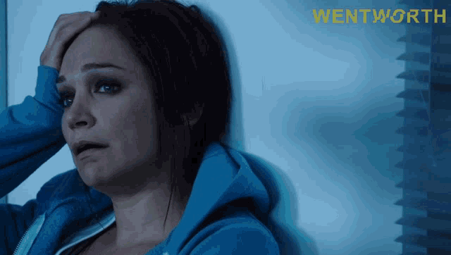 a woman leaning against a wall with wentworth written on the bottom right