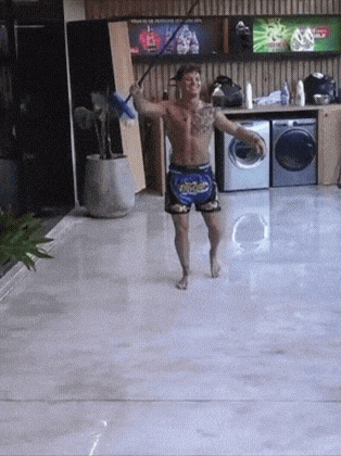 a shirtless man is dancing with a mop in his hand