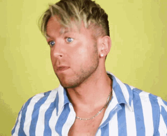 a man wearing a blue and white striped shirt with a necklace around his neck