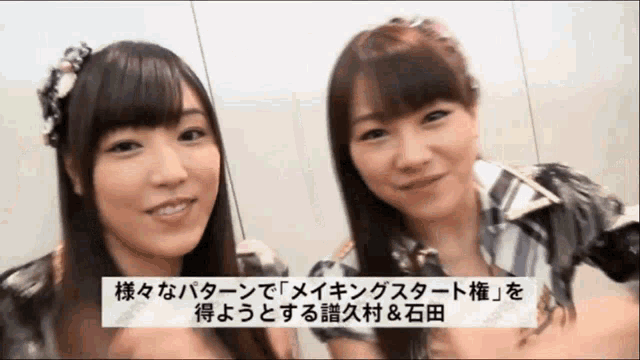 two asian girls are smiling in front of a sign that says ' a & a ' on it