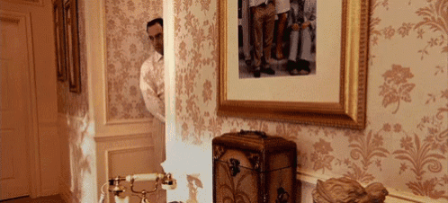 a man stands in a hallway with a picture on the wall behind him