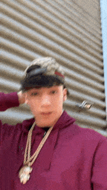 a man wearing a hat and a necklace is standing in front of a building .