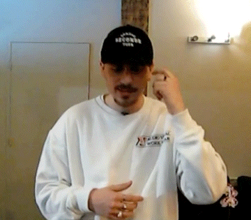 a man wearing a white sweatshirt and a black hat with the word records on it