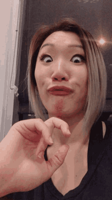 a woman is making a funny face with her hand