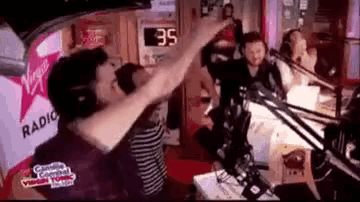 a group of people are dancing in front of a virgin radio station