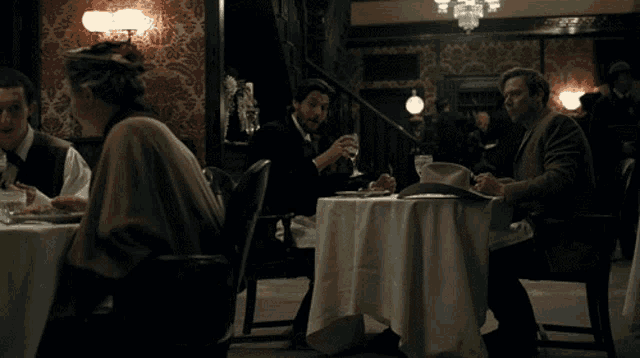 a man in a hat sits at a table in a restaurant with other people