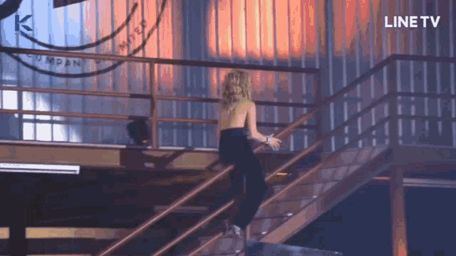 a woman is walking down a set of stairs with a line tv logo on the bottom
