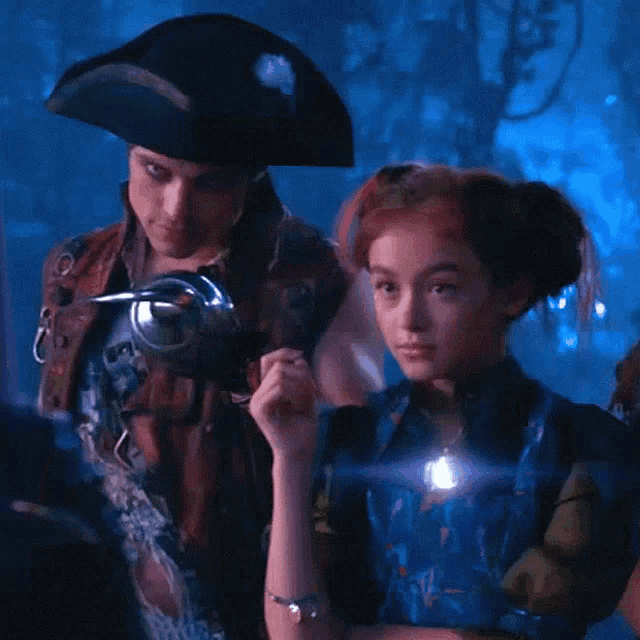 a man in a pirate hat is standing next to a girl in a blue dress