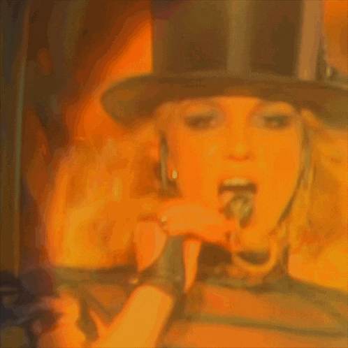 a woman wearing a top hat is singing into a microphone .