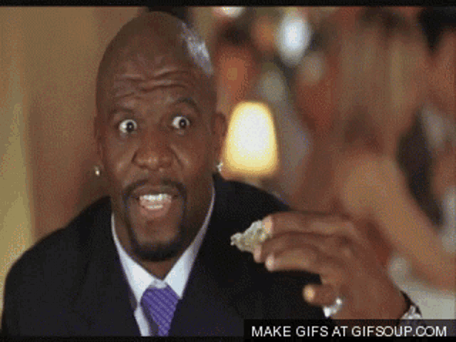 a man in a suit and tie is holding something in his hand with a make gifs at gifsoup.com watermark visible