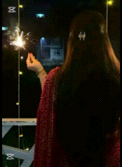 a girl is holding a sparkler with the name priya on her back