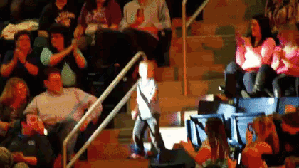 a young boy stands in front of a crowd in a stadium wearing a shirt that says ' texas ' on it