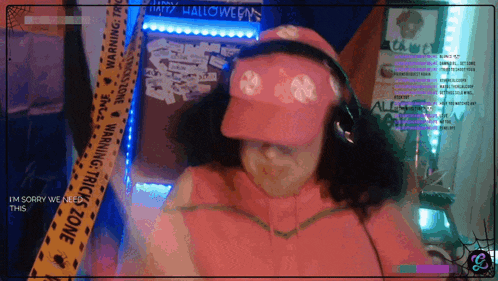 a woman wearing a pink hat and headphones is standing in front of a halloween decoration