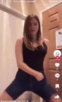 a woman in a black top and shorts is dancing in a room