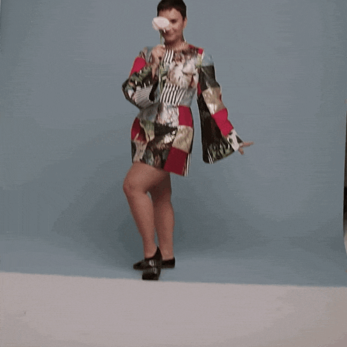 a woman in a colorful dress holds a conch shell in her hand