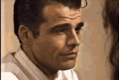 a man in a white shirt and tie is looking at a woman in a room .