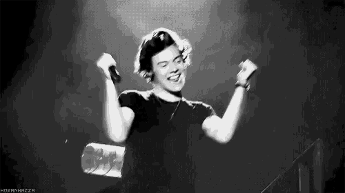 harry styles is wearing headphones and holding a microphone in his hands while dancing on stage .