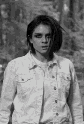 a black and white photo of a woman wearing a denim jacket .