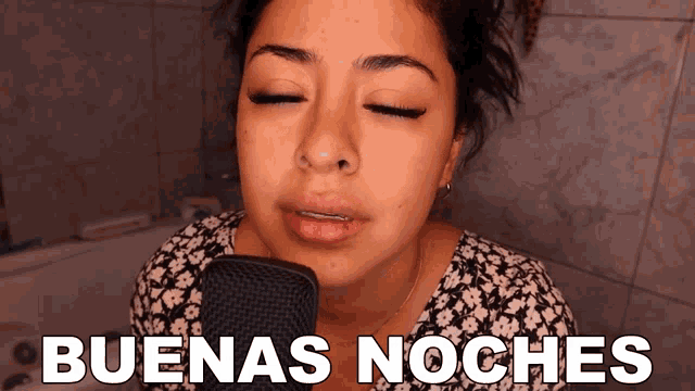a woman singing into a microphone with the words " buenas noches " below her