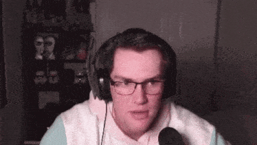 a man wearing glasses and headphones is speaking into a microphone .