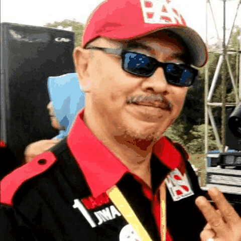 a man wearing sunglasses and a red hat with the letter b on it