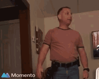 a man in a brown shirt is standing in front of a television with the words momento on the bottom