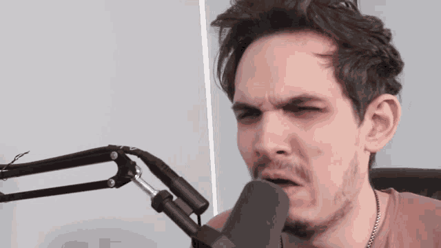 a man with a beard is talking into a microphone and making a funny face