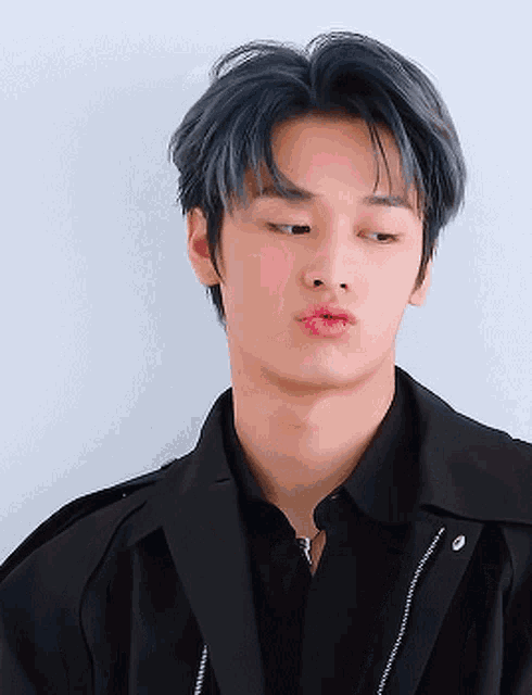 a young man with blue hair and pink lips is wearing a black jacket and a black shirt .