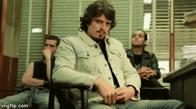 a man with a beard is sitting in a chair smoking a cigarette .