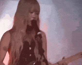 a woman is playing a guitar and singing into a microphone on stage .