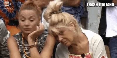 two women are sitting next to each other in a crowd . one of the women is crying .
