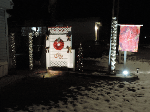 a christmas wreath hangs on a white door in the snow