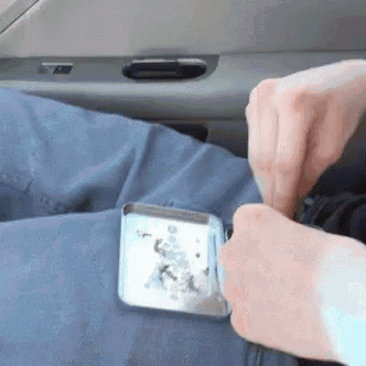 a person is sitting in a car holding a tin with a picture of a christmas tree on it .
