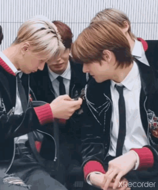 a group of young men in suits and ties are looking at a cell phone with xrecorder written in the corner