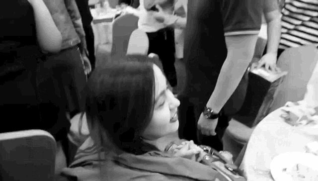 a woman is sitting at a table in a black and white photo .