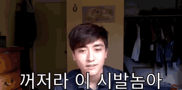 a young man stands in front of a closet with korean writing on the wall