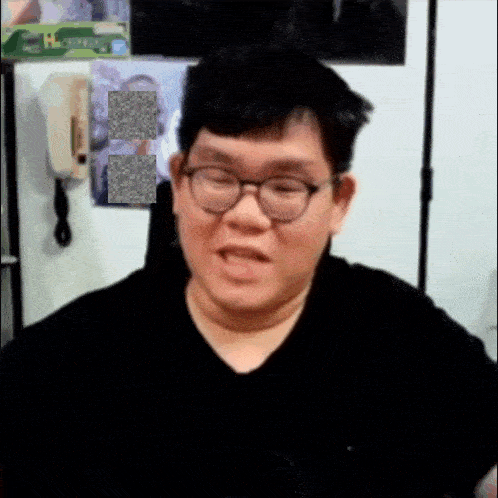 a man with glasses and a black shirt is making a funny face .